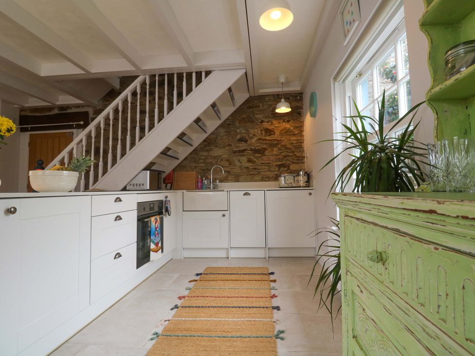 A kitchen with a staircase and green cabinet at Cubs Corner in St Agnes