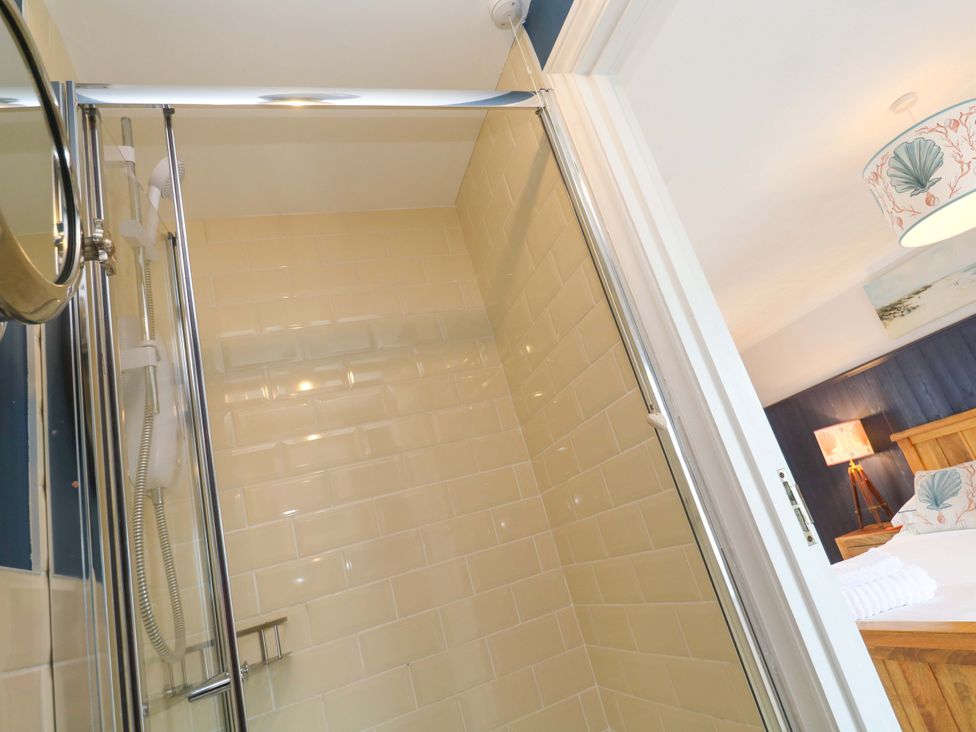 A shower area with tiled walls and a doorway at Cubs Corner in St Agnes