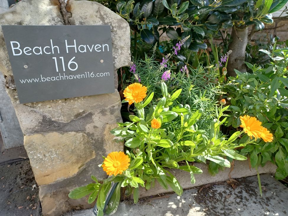 A sign for Beach Haven 116 with flowers at Beach Haven 116 in Leven