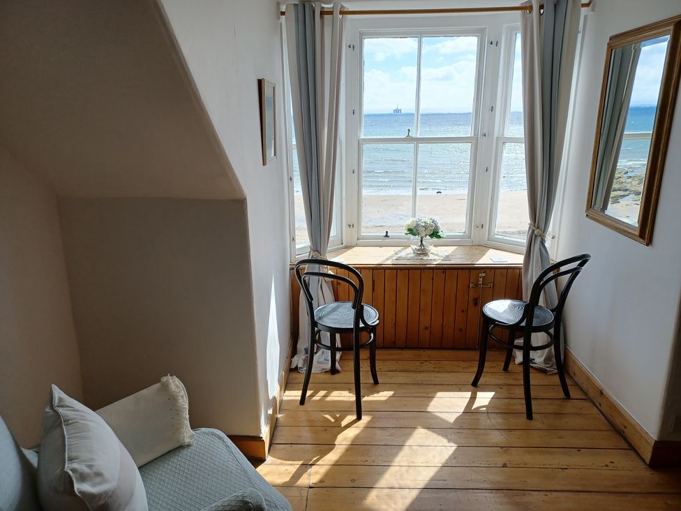 A sitting room with a window and two chairs at Beach Haven 116 Leven