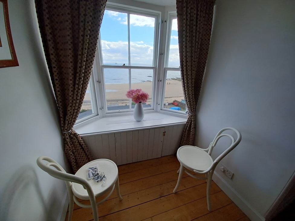 A sitting room with a table and chairs overlooking the beach at Beach Haven 116 Leven