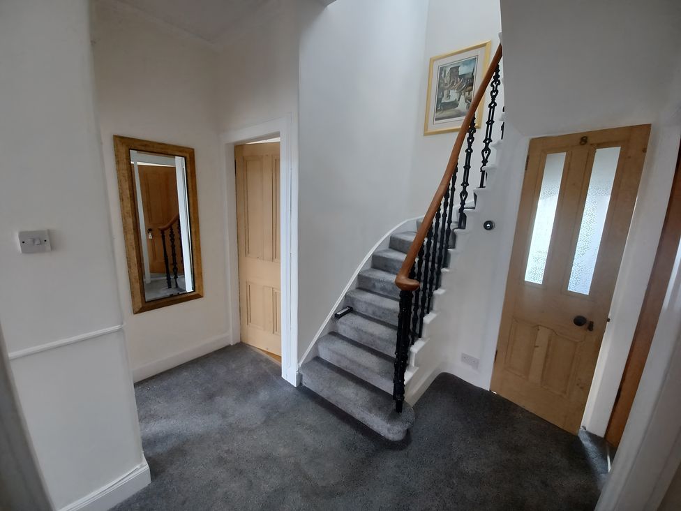 A hallway with a staircase and a mirror at Beach Haven 116 in Leven