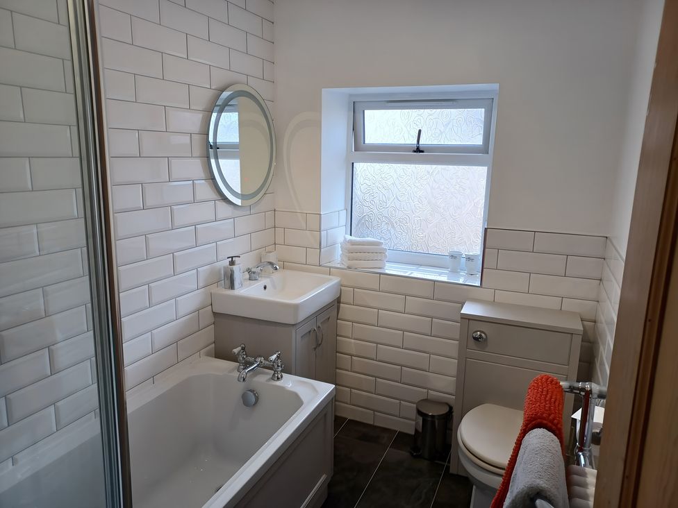 A bathroom with a sink, bathtub, toilet, and window at Beach Haven 116 Leven