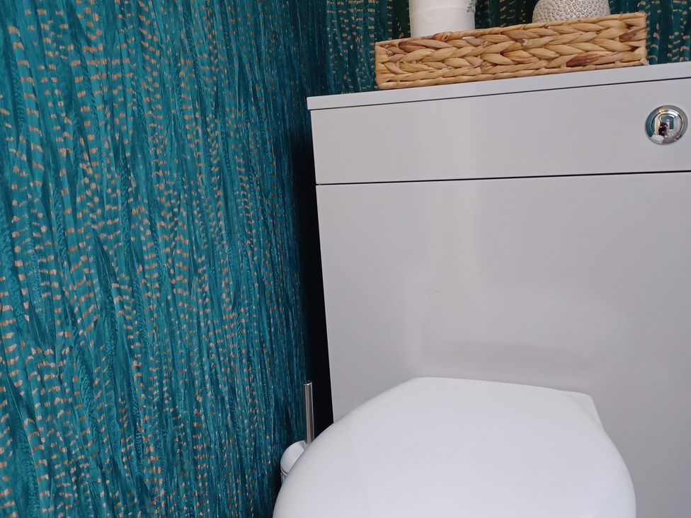 A bathroom with a toilet and storage cabinet at Beach Haven 116 in Leven