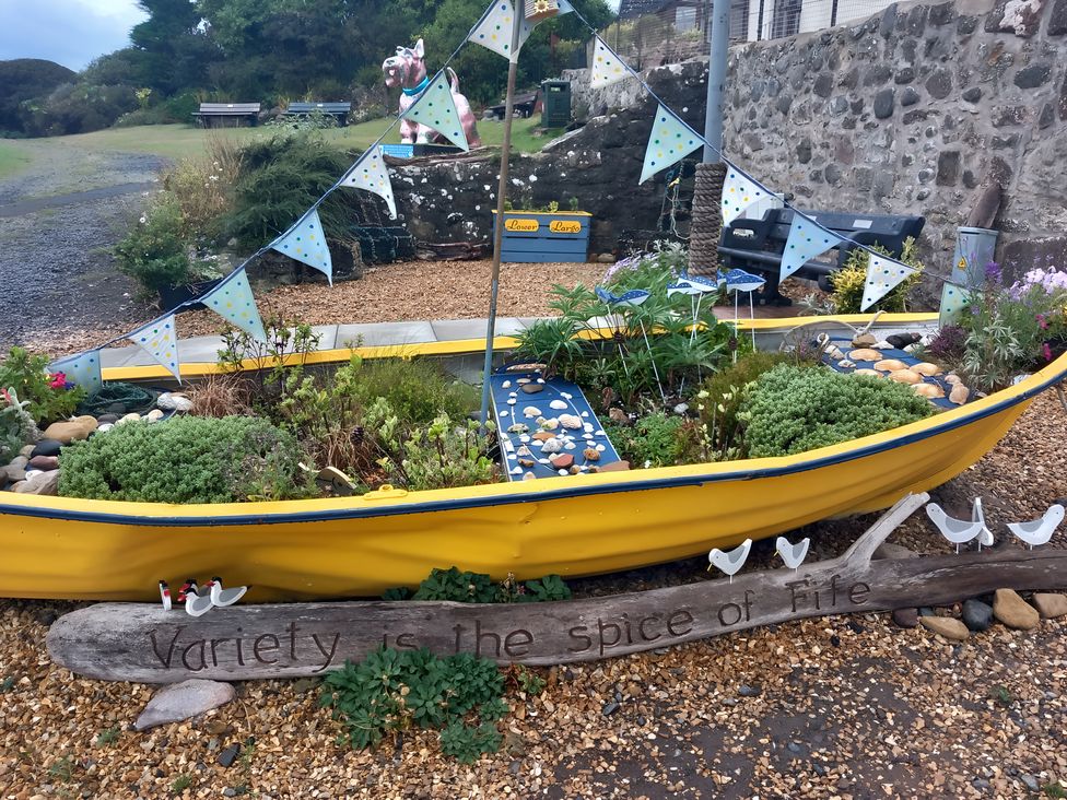 A boat planted with flowers and decorated with bunting at Beach Haven 116 Leven