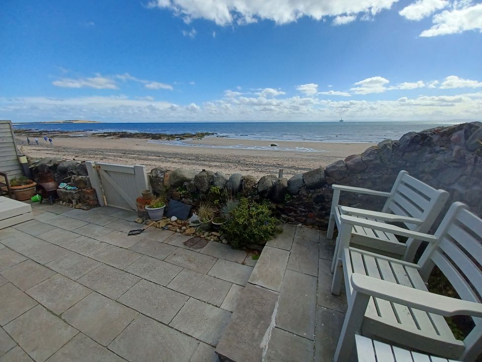 A beach view from a patio with chairs at Beach Haven 116 Leven
