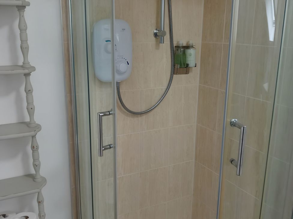 A bathroom with a shower and storage shelf at 14 Largo Road in Leven