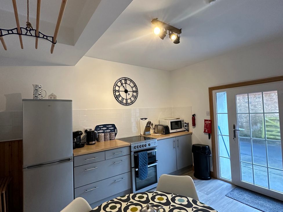 A kitchen featuring appliances and a dining table at Coastal Cottage in Anstruther