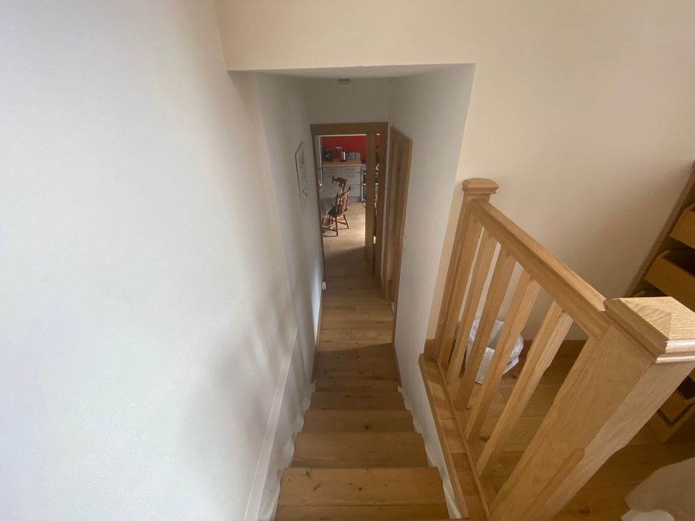 A staircase leading down towards a kitchen area at Coastal Cottage Anstruther