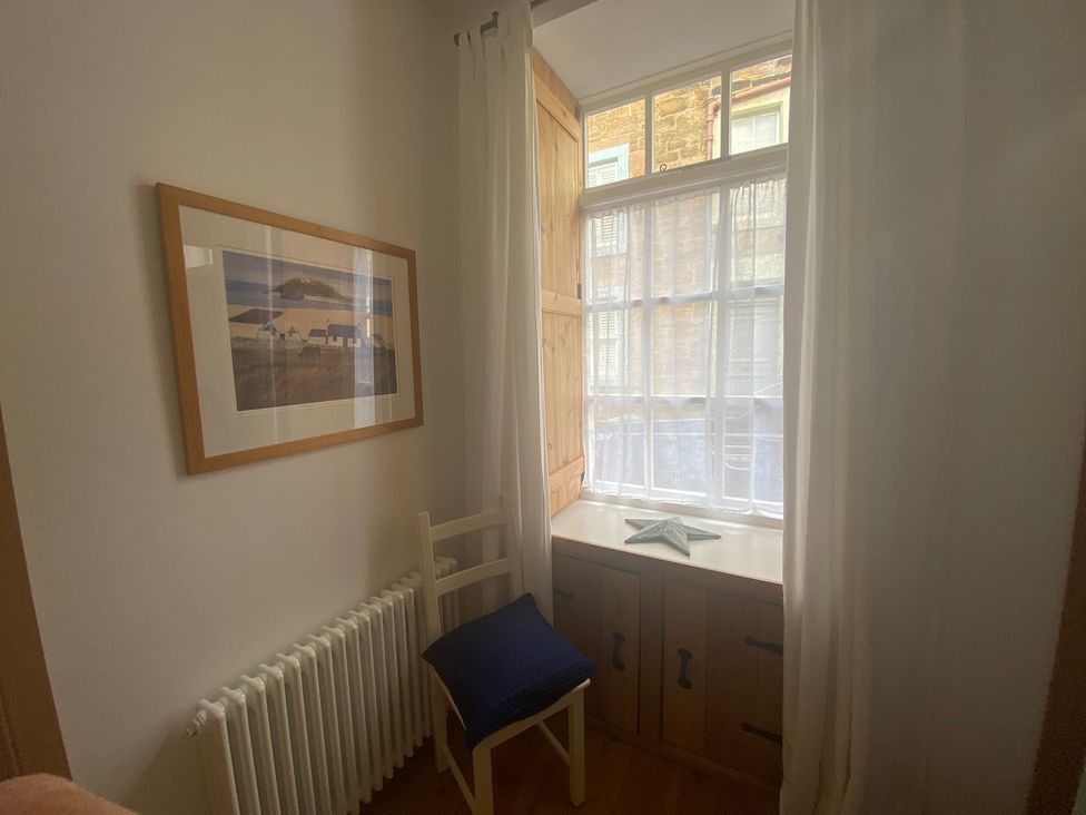 A nook with a window, chair, and a cabinet at Coastal Cottage in Anstruther