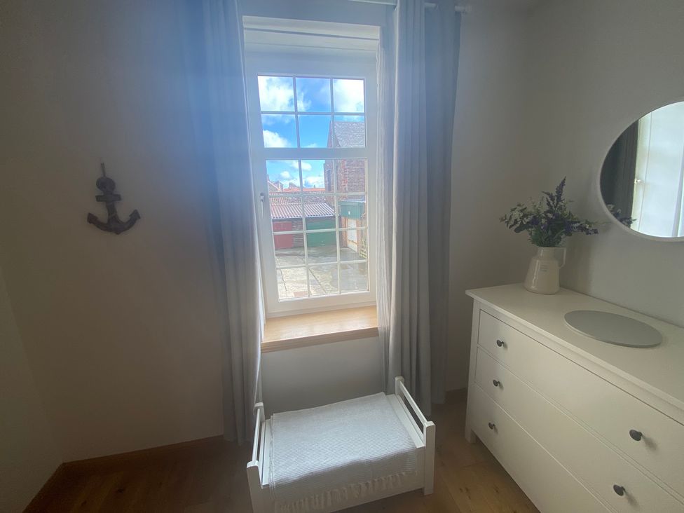 A bedroom with a window, dresser and mirror at Coastal Cottage Anstruther