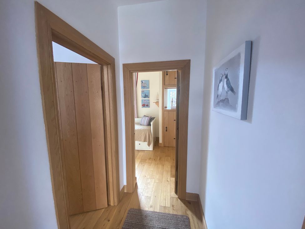 A hallway with doors and wooden flooring at Coastal Cottage Anstruther