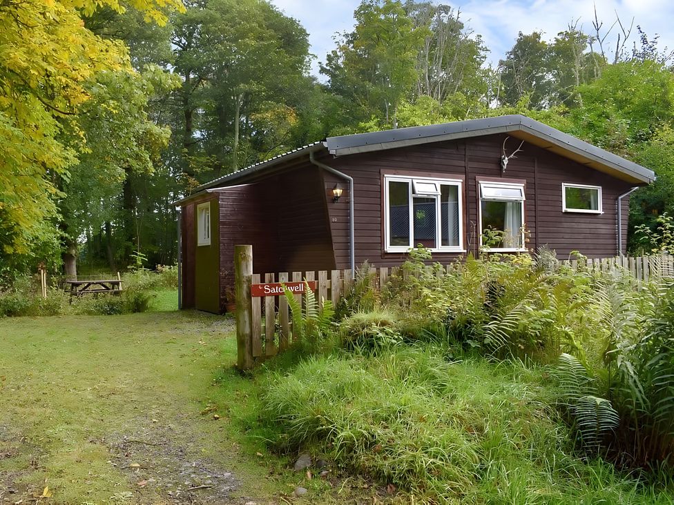A cabin surrounded by trees and grass at Satchwell Chalet in Inverness