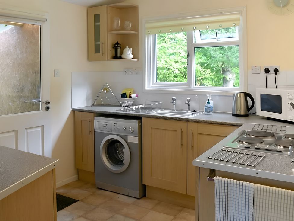 A kitchen with washing machine and cooking stove at Satchwell Chalet Inverness