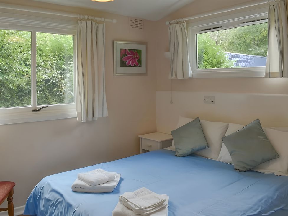 A bedroom with a bed and windows at Satchwell Chalet in Inverness