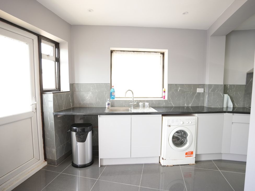 A kitchen with a sink and washing machine at Westwick Gardens Retreat in Hounslow