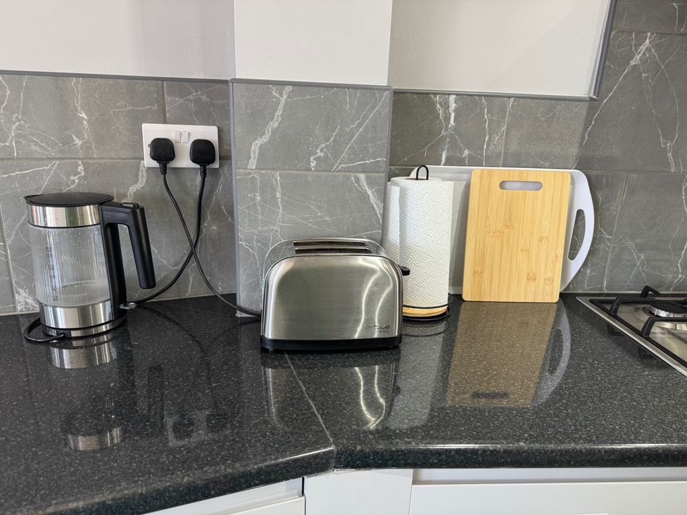 A kitchen countertop with a toaster, kettle, and cutting board at Westwick Gardens Retreat in Hounslow