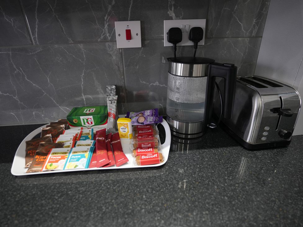A kitchen with a kettle, toaster, and a tray of beverages and snacks at Westwick Gardens Retreat in Hounslow