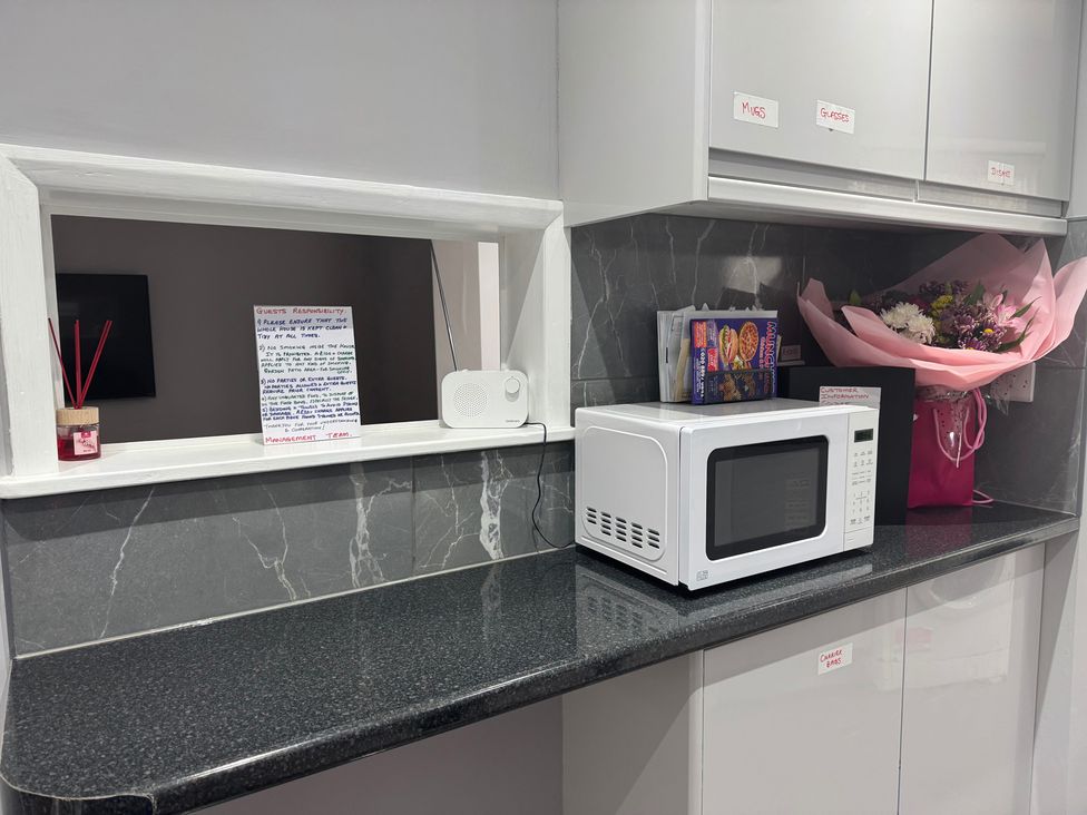 A kitchen with a microwave and a flower bouquet at Westwick Gardens Retreat in Hounslow