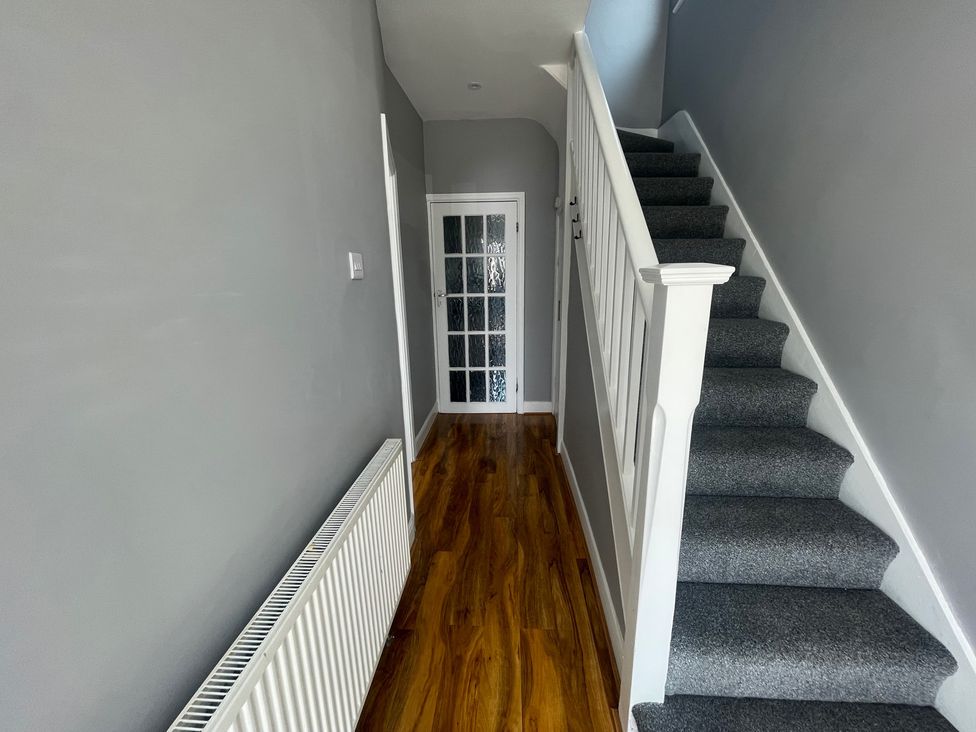 A hallway with stairs and a door at Westwick Gardens Retreat in Hounslow