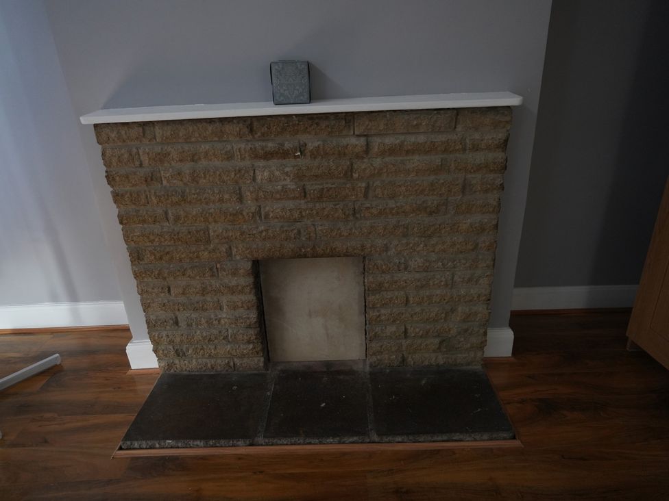 A stone fireplace with a wooden floor at Westwick Gardens Retreat in Hounslow
