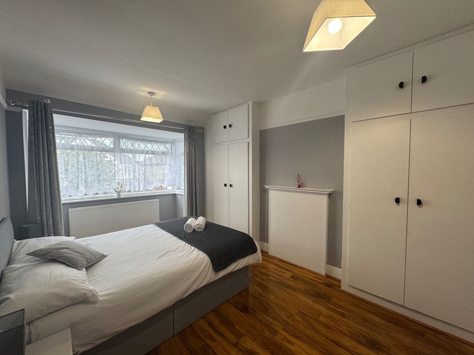 A bedroom with a bed and wardrobes at Westwick Gardens Retreat in Hounslow