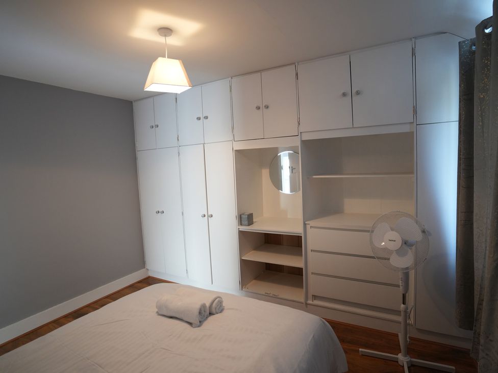A bedroom with a bed, wardrobe, mirror, and fan at Westwick Gardens Retreat in Hounslow