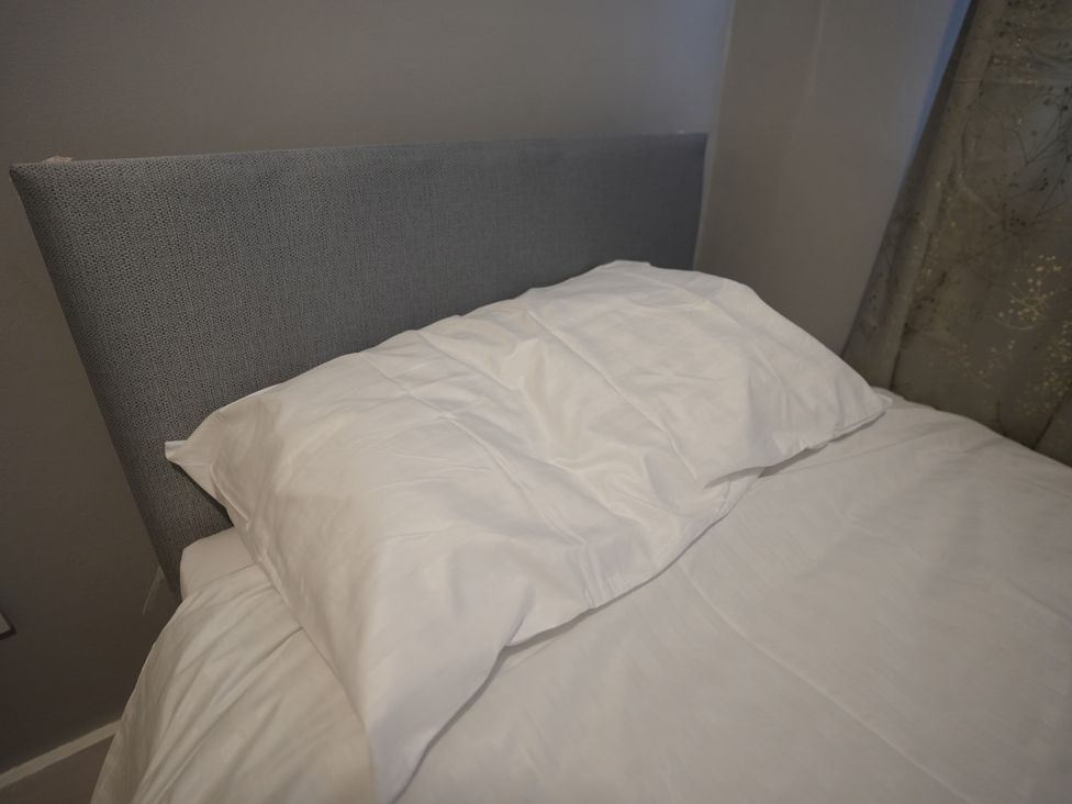 A bed with a gray headboard and white pillows at Westwick Gardens Retreat Hounslow