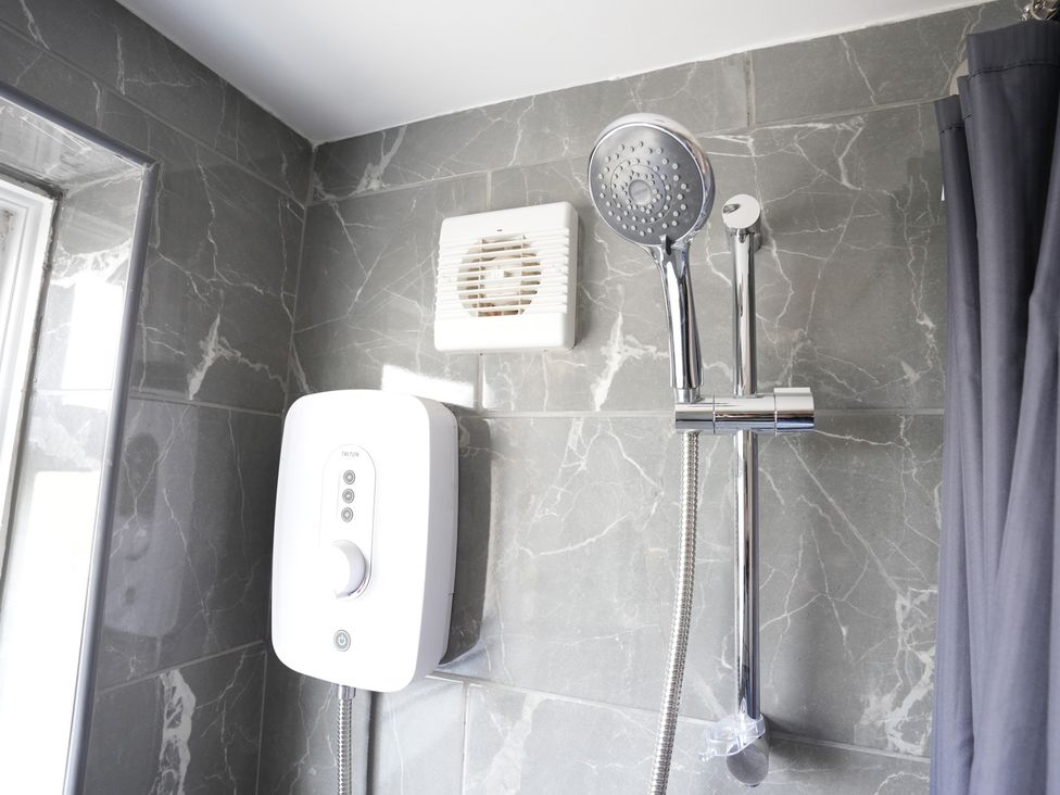A bathroom featuring a showerhead, control unit, and exhaust fan at Westwick Gardens Retreat in Hounslow