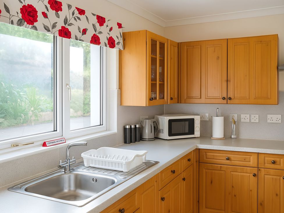 A kitchen with wooden cabinets and a sink at Culnacraig in Stranraer
