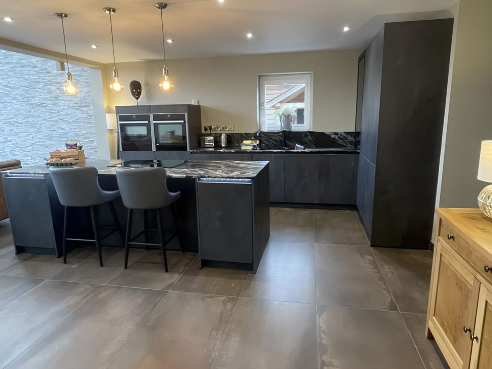 A kitchen with a black island and stools at Pendle View in Preston