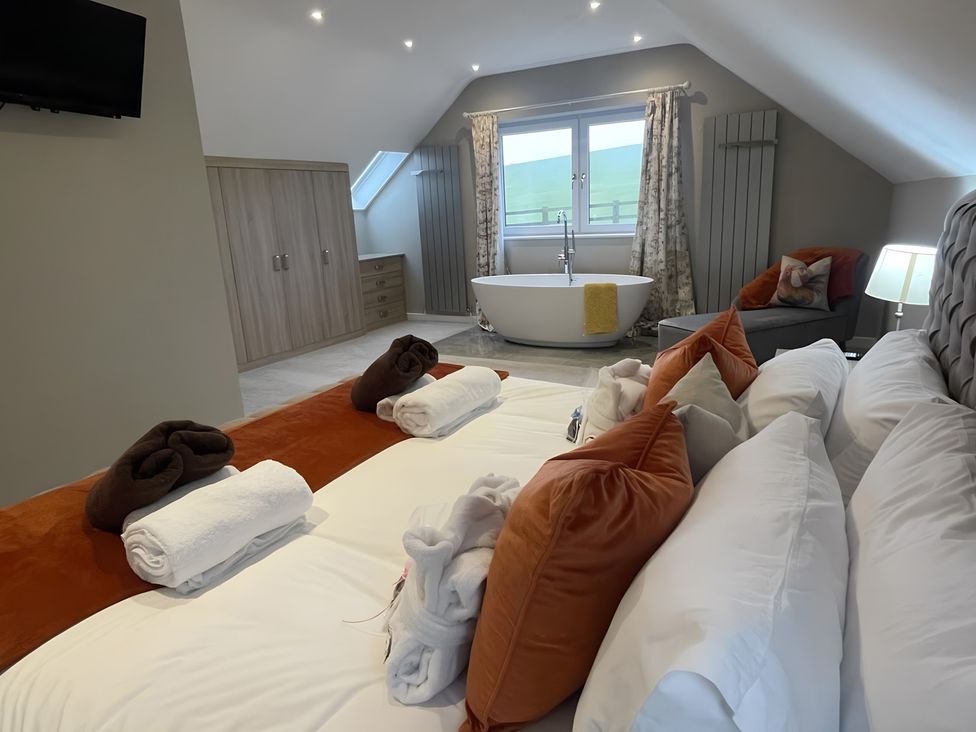 A bedroom with a bathtub and seating area at Pendle View in Preston