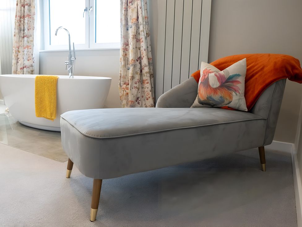 A bathroom with a bathtub and a chaise lounge at Pendle View in Preston