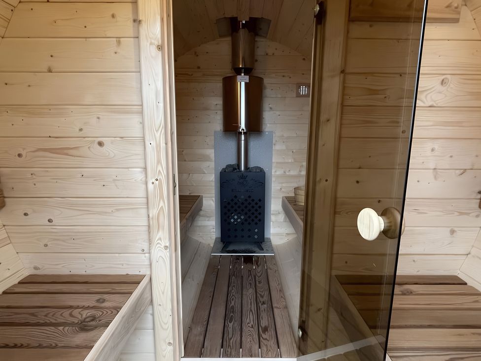 A sauna with wooden walls and benches and a stove at Pendle View Preston