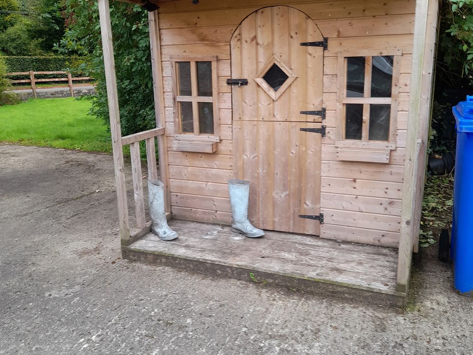 A small wooden shed with boots outside at The Farmhouse in Omagh
