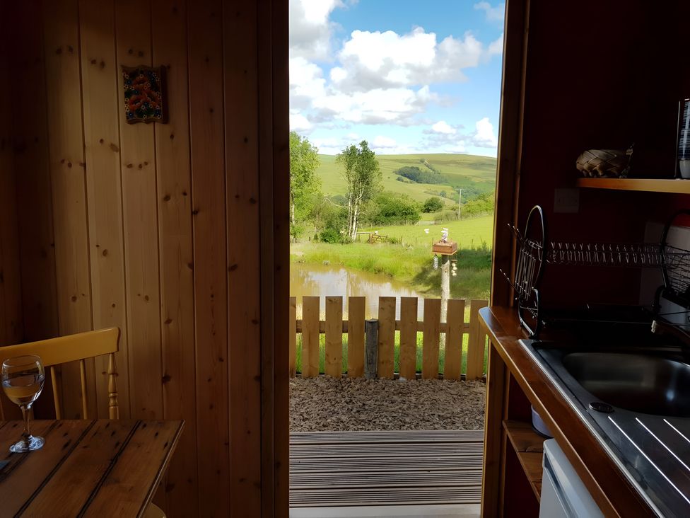 A kitchen with a view of the landscape and water at Bryn Mawr Cabin in Craven Arms