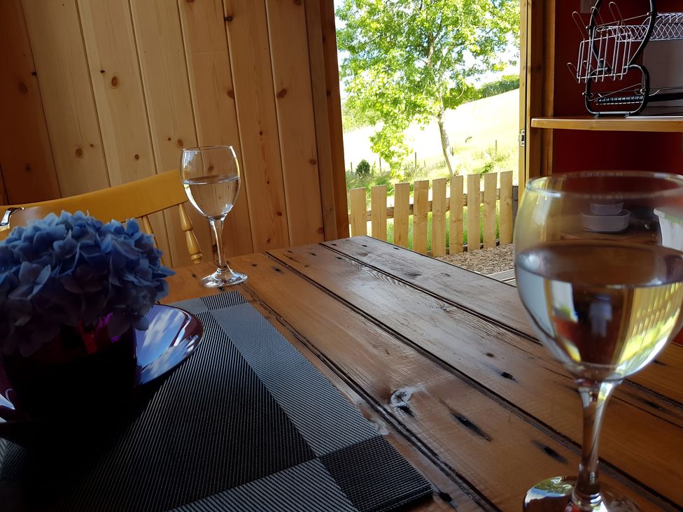 A dining room with a table, glasses, and flowers at Bryn Mawr Cabin in Craven Arms