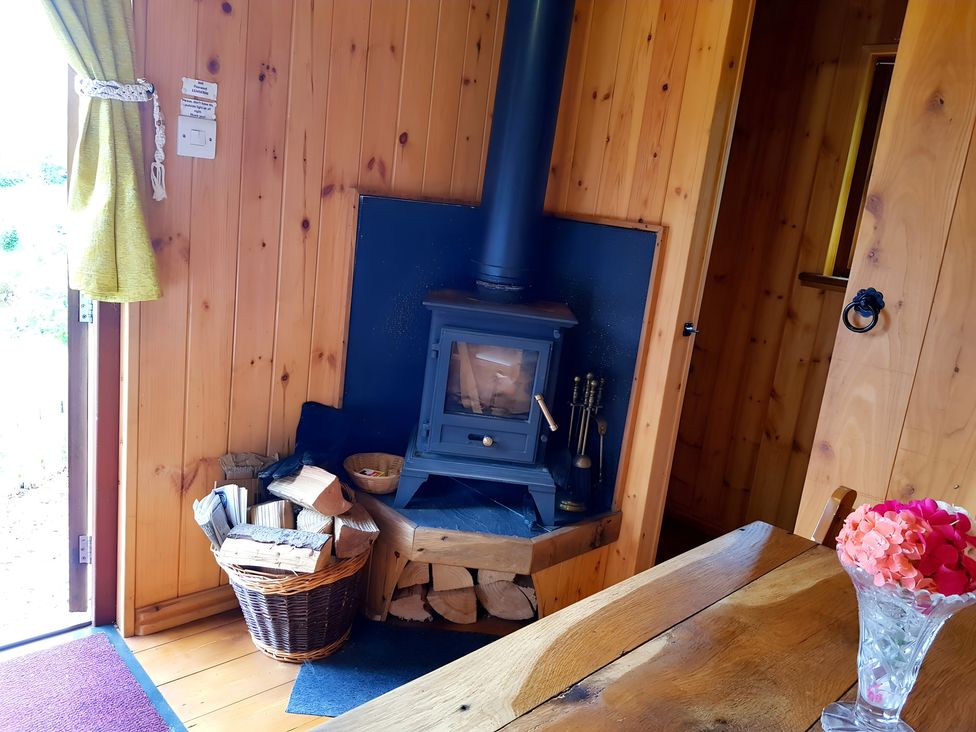 A living room featuring a wood stove and a table at Bryn Mawr Cabin in Craven Arms
