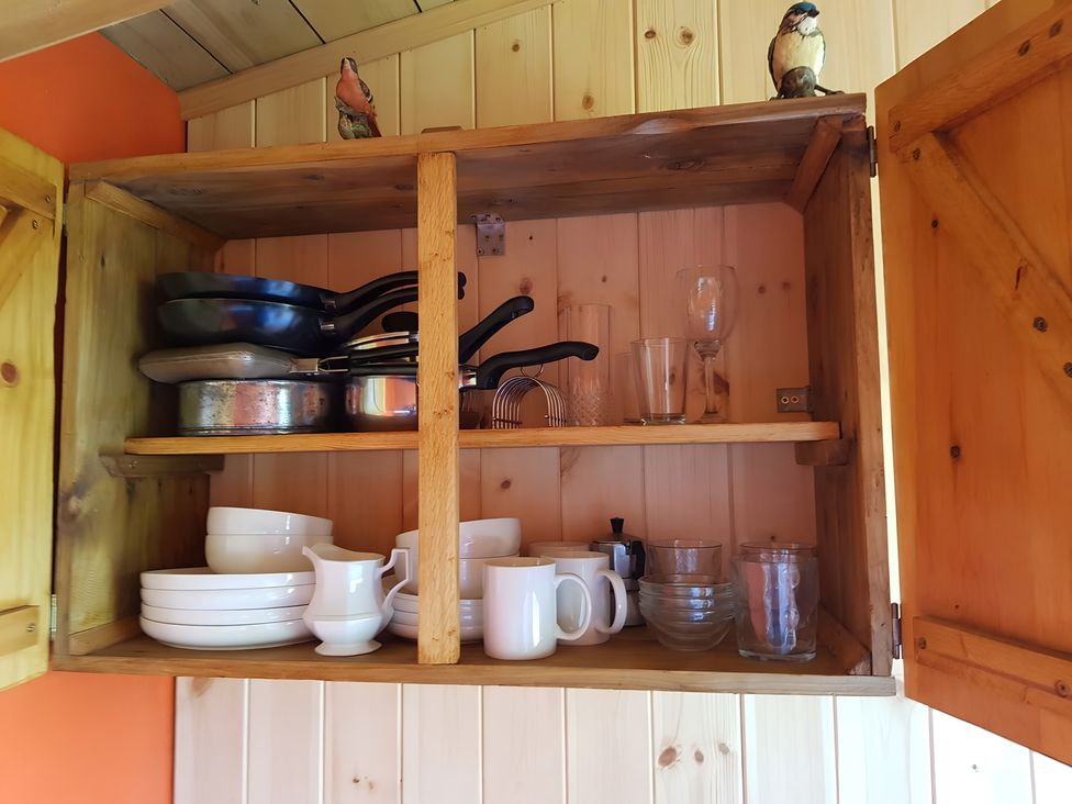A cupboard with cooking pans and glassware at Bryn Mawr Cabin in Craven Arms