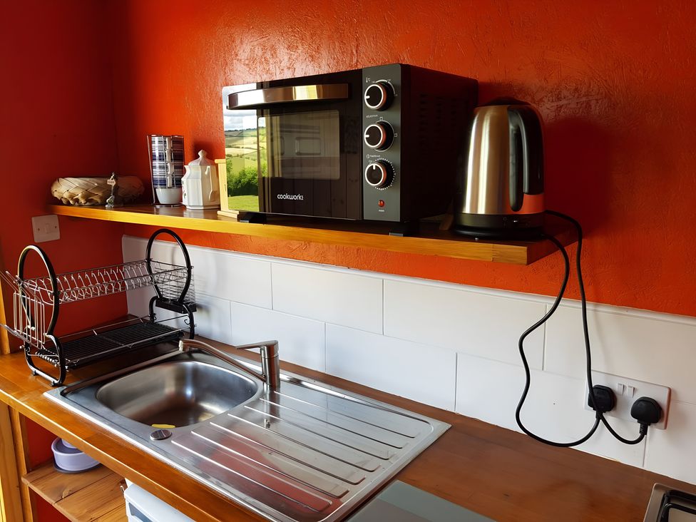 A kitchen with a microwave, kettle, and sink at Bryn Mawr Cabin in Craven Arms