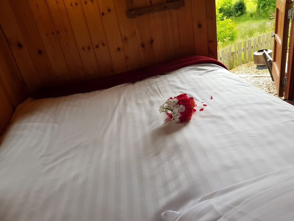 A bed with flowers on the sheets at Bryn Mawr Cabin in Craven Arms
