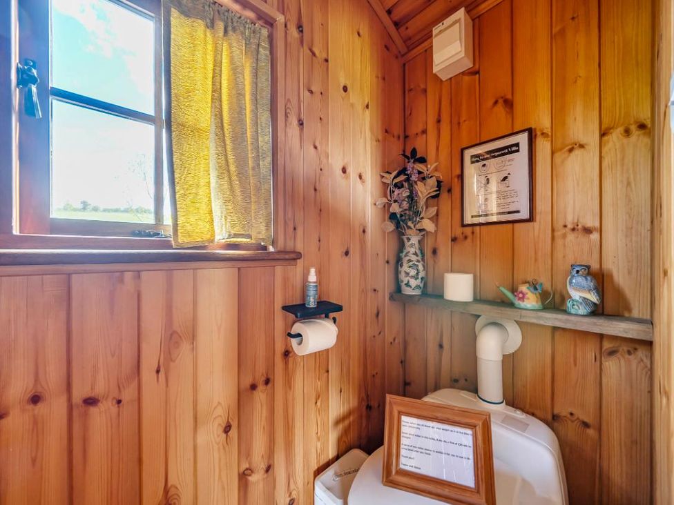 A bathroom with wooden walls and a toilet at Bryn Mawr Cabin Clun