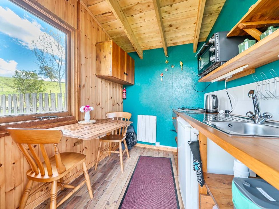 A kitchen with wooden cabinets and a table in Bryn Mawr Cabin Clun