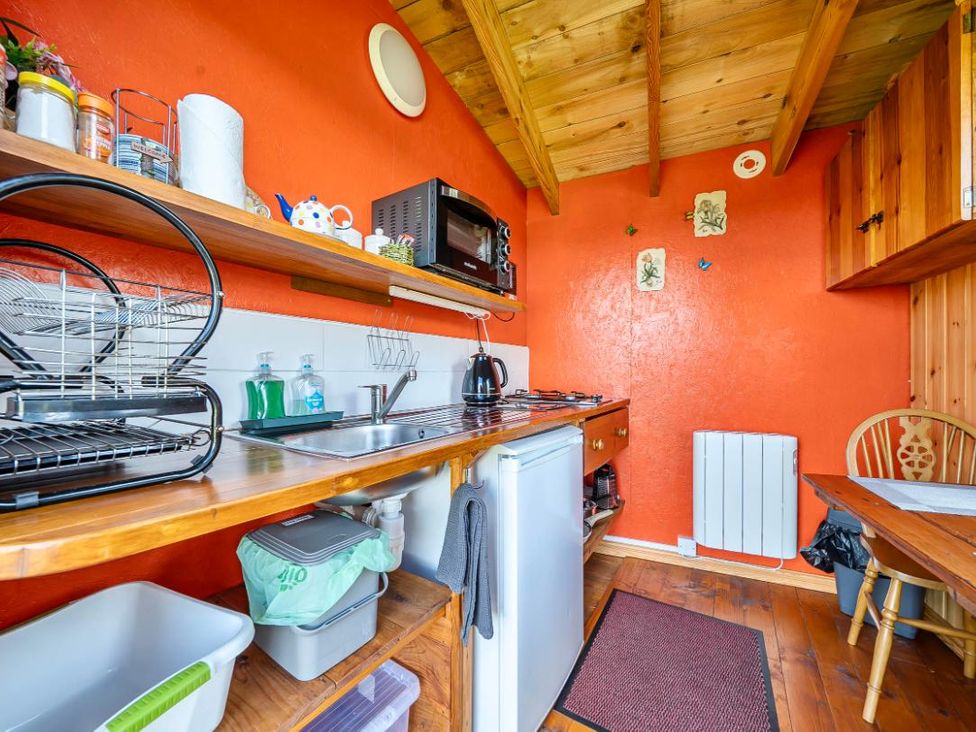 A kitchen with shelves and appliances at Bryn Mawr Cabin in Clun