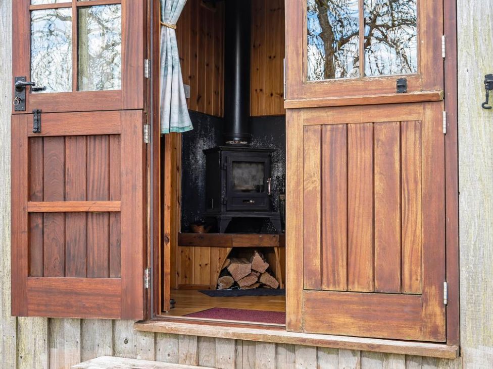 A cabin entrance with a wood stove and logs at Bryn Mawr Cabin in Clun
