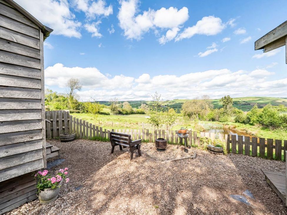 A garden with a bench and fire pit at Bryn Mawr Cabin in Clun