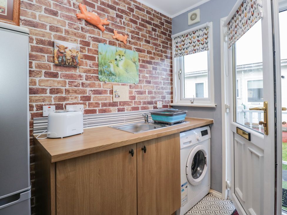 A kitchen with a washing machine and sink at Beechtree Lodge 46 in Denny