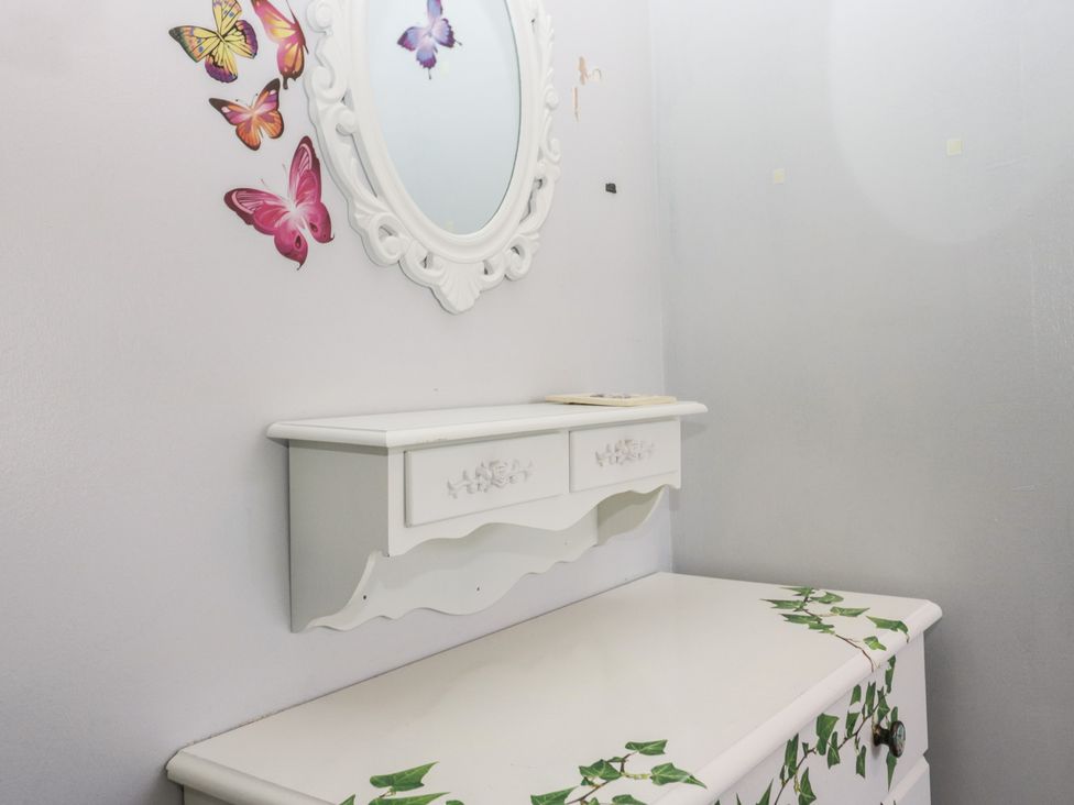 A dresser with a mirror and butterflies on the wall at Beechtree Lodge 46 Denny