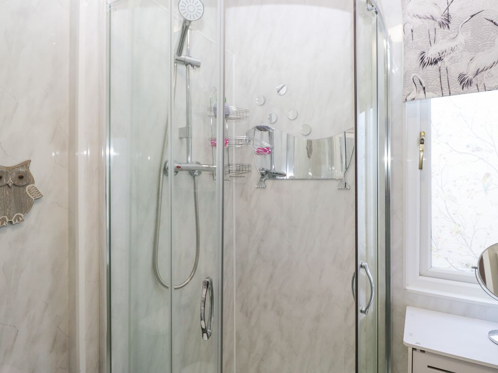 A shower with glass doors and a mirror at Beechtree Lodge 46 in Denny