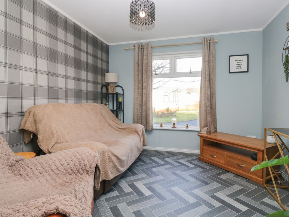 A living room with a sofa and shelving unit at Beechtree Lodge 56 Denny